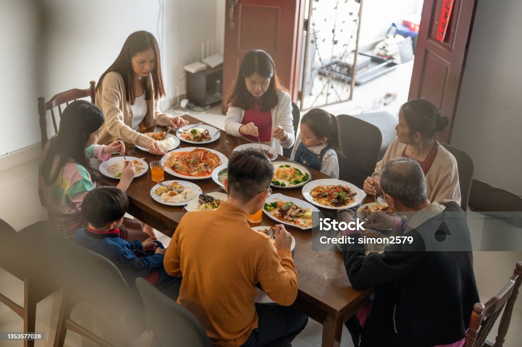 Three generations of joyful Asian family celebrating and enjoying reunion dinner at home during Chinese New Year Three generations of joyful Asian family celebrating and enjoying reunion dinner at home during Chinese New Year. Bonding and Togetherness Concepts. Family Stock Photo