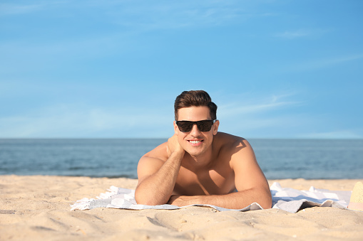 Happy man with slim body resting on beach