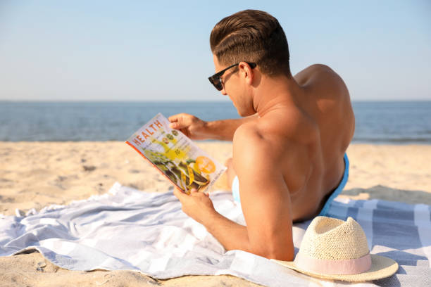 istock Man with slim body resting on beach 1353578446