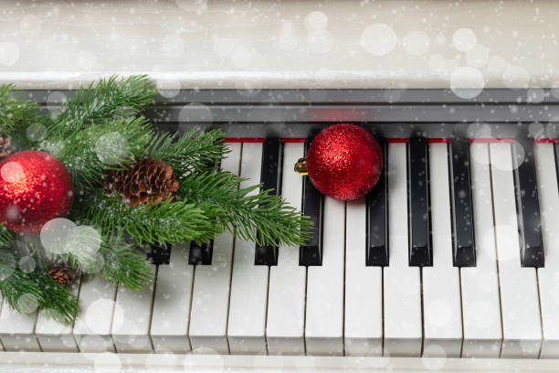 New Year or Christmas music concept. piano with a branch of a Christmas tree, pine cones and red Christmas balls stock photo