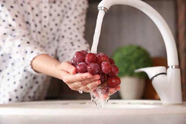 istock Woman washing fresh grapes in kitchen sink, closeup 1353580418