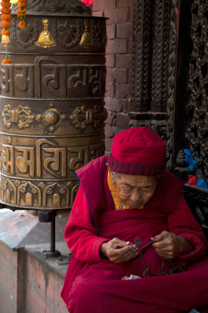 vieille femme dans un stupa bouddhiste emblématique, katmandou, népal. - bodnath stupa photos et images de collection
