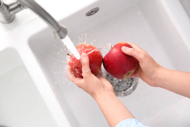 istock Woman washing fresh red apples in kitchen sink, top view 1353581596