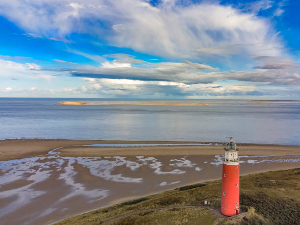 Lighthouse at the Wadden island Texel in the dunes during a calm autumn afternoon with reflections on the North Sea beach. The Eierland lighthouse is located at the North point of the island.