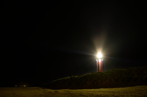 Lighthouse at the Wadden island Texel in the dunes at night with a footpaht leading up to the lighthouse.