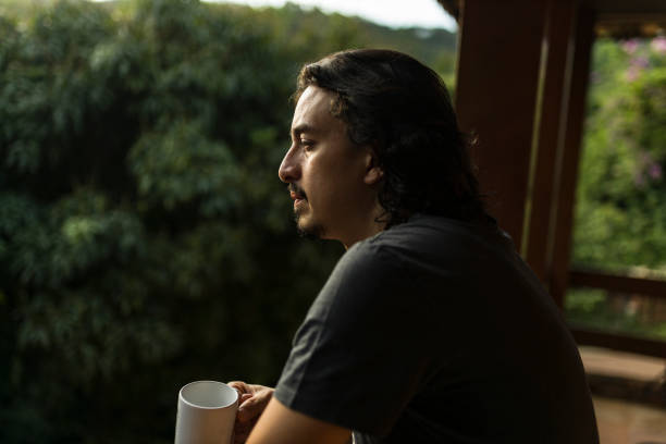 istock Man drinking coffee or tea on porch amid nature 1353585681