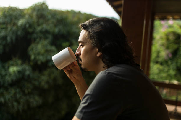 istock Man drinking coffee or tea on porch amid nature 1353585691