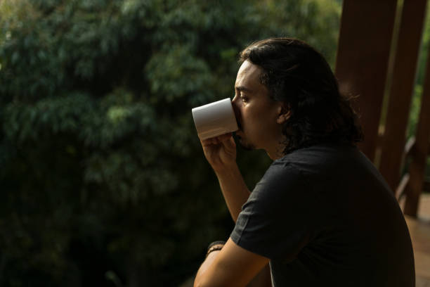 istock Man drinking coffee or tea on porch amid nature 1353585701