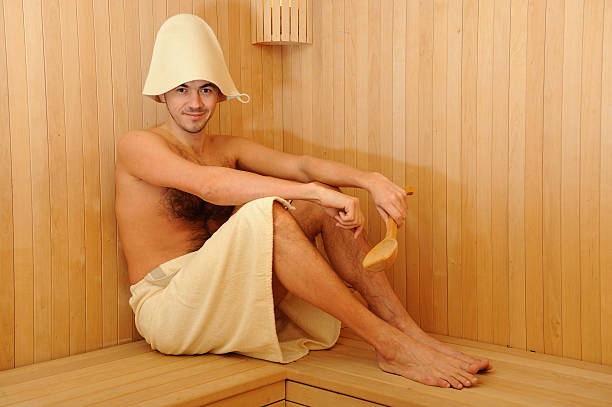 Young handsome man in a towel relaxing russian wooden sauna stock photo