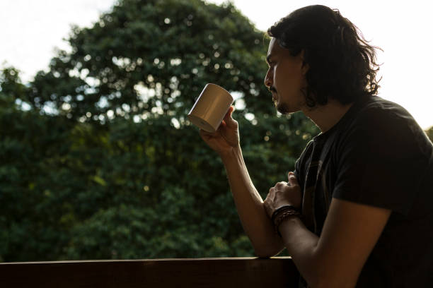 istock Man drinking coffee or tea on porch amid nature 1353585727