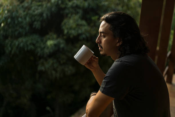 istock Man drinking coffee or tea on porch amid nature 1353585730
