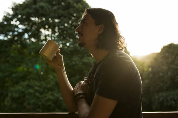 istock Man drinking coffee or tea on porch amid nature 1353585739