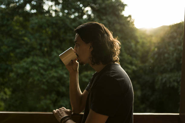 istock Man drinking coffee or tea on porch amid nature 1353585753