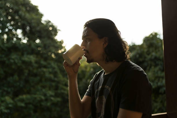 istock Man drinking coffee or tea on porch amid nature 1353585777
