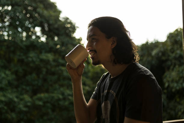 istock Man drinking coffee or tea on porch amid nature 1353585790