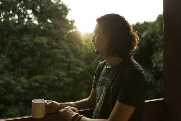 istock Man drinking coffee or tea on porch amid nature 1353585798