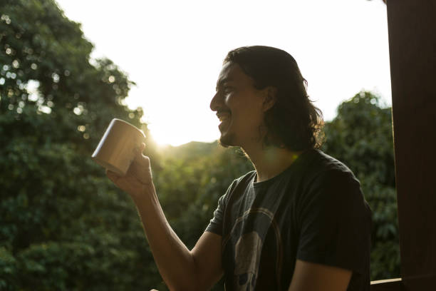 istock Man drinking coffee or tea on porch amid nature 1353585821