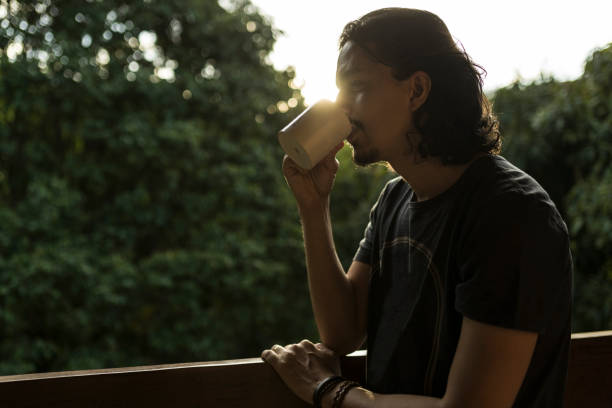 Man drinking coffee or tea on porch amid nature