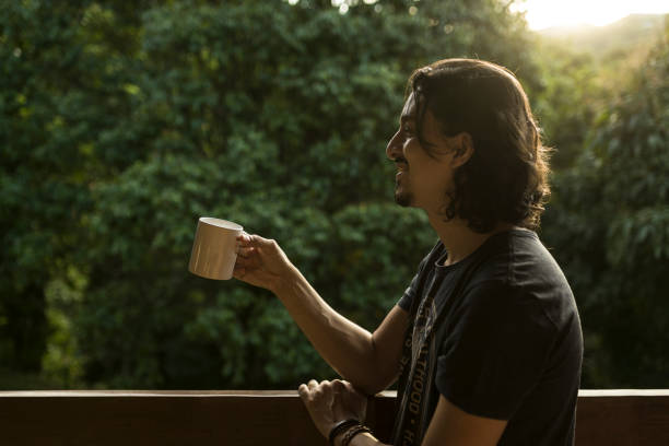 istock Man drinking coffee or tea on porch amid nature 1353585871