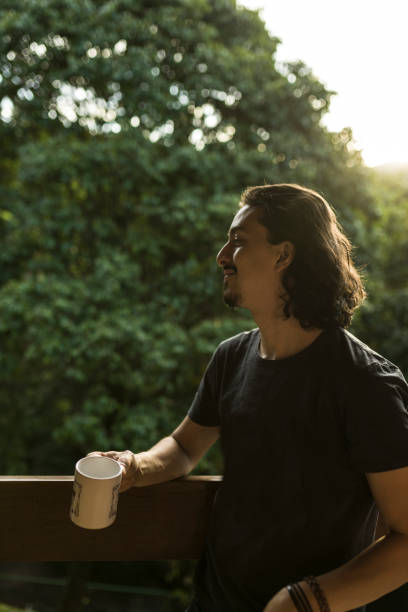 istock Man drinking coffee or tea on porch amid nature 1353585878