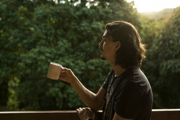 istock Man drinking coffee or tea on porch amid nature 1353585896