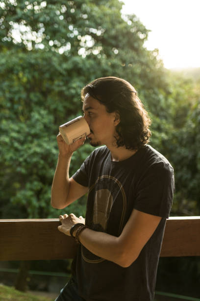 istock Man drinking coffee or tea on porch amid nature 1353585913