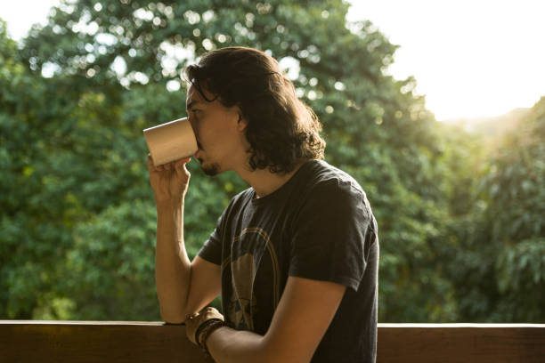 istock Man drinking coffee or tea on porch amid nature 1353585930