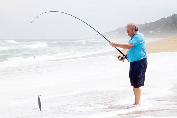 istock senior man catching fish on beach 135358594