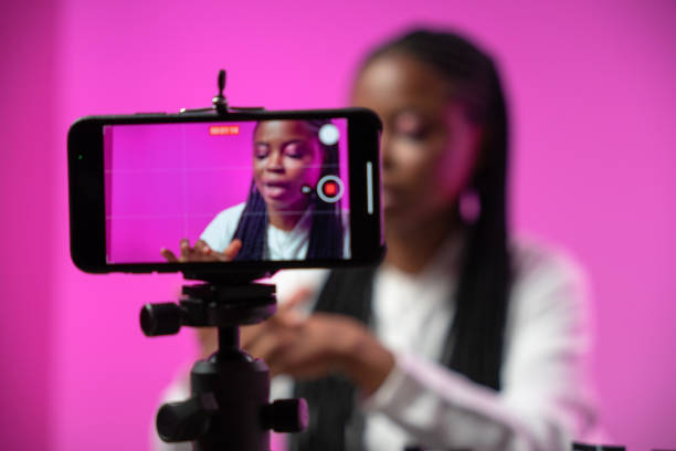 istock A smartphone screen in the foreground with a young dark-skinned blogger on a pink background on it 1353589715