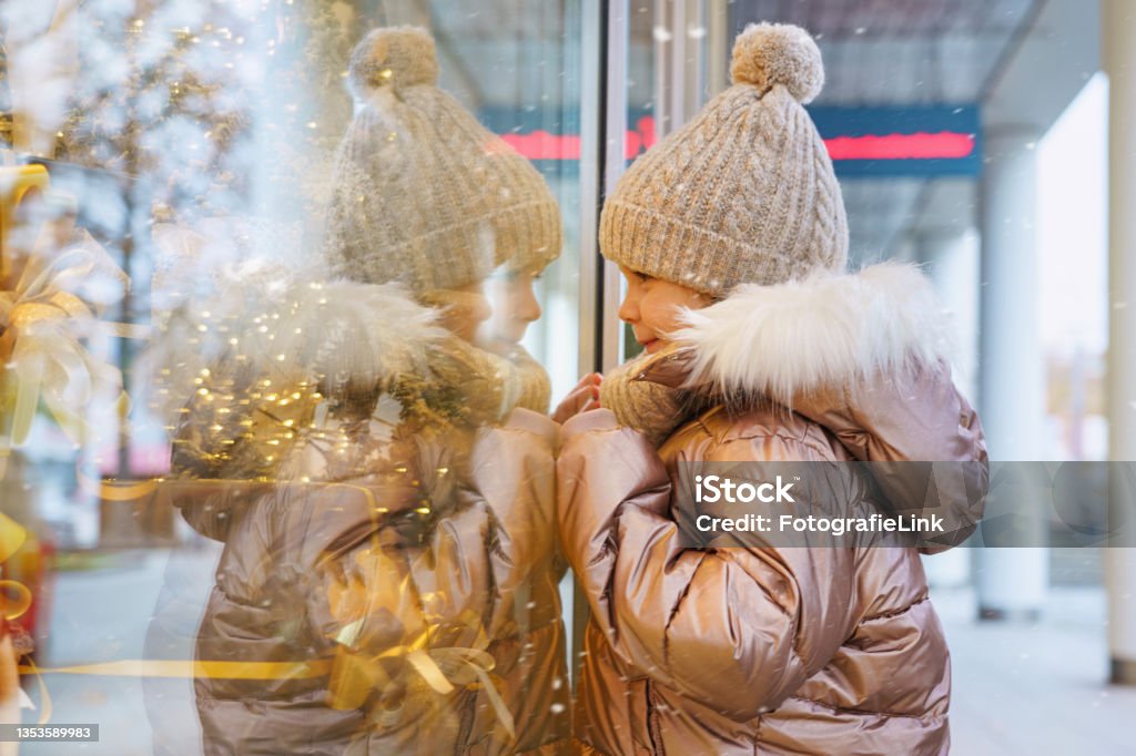 little child looks at a Christmas decorated shop window Store Window Stock Photo