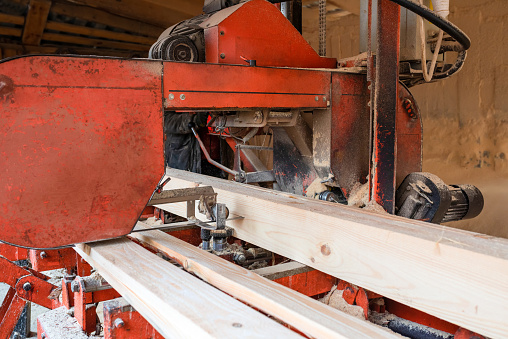 Processing wooden boards at a sawmill. The process of processing logs in the equipment of a sawmill saw a tree trunk on boards.