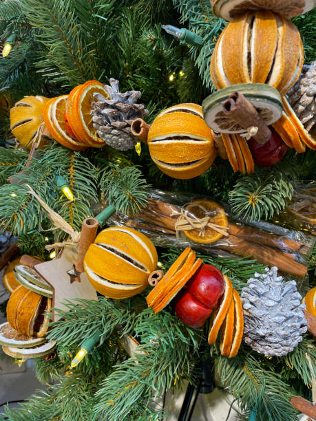 imagen de decoraciones de árboles de navidad, guirnaldas de frutas secas de cítricos, naranjas enteras secas, rodajas de lima, palitos de canela y piñas, agujas de abeto verde, fondo borroso de luces de hadas blancas - christmas tree decorations indoors selective focus arrangement fotografías e imágenes de stock