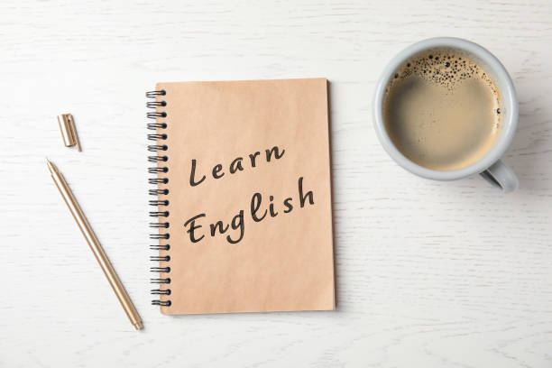 istock Notebook with text Learn English and cup of coffee on wooden table, flat lay 1353591686