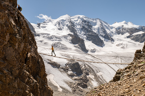 Female climbing in summer on Via Ferrata in Switzerland.\nGlacier in distance