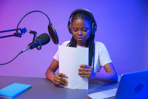 istock Blogger, recording a podcast with a stack of paper in hands 1353592274