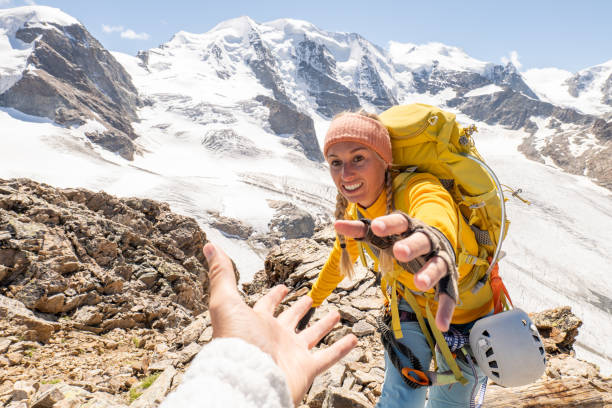 kletterer hilft teamkollegen mit helfende hand - climbing women sport mountain stock-fotos und bilder