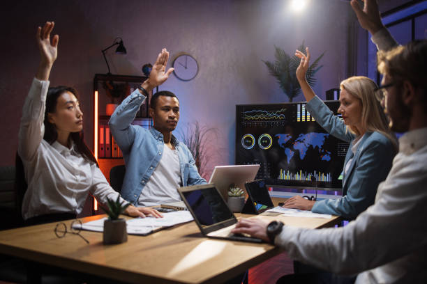 istock Four multiracial office colleagues sitting at the table with arms raised 1353593557