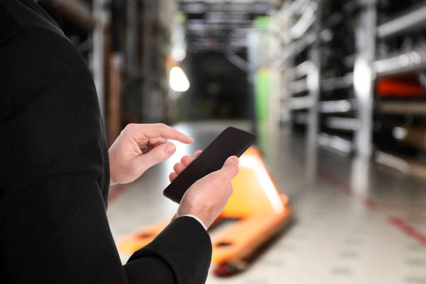 istock Wholesale trading. Man using WMS app on smartphone at warehouse, closeup 1353594978