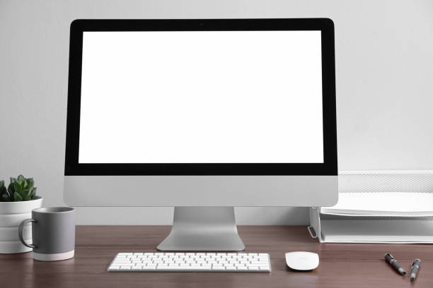 istock Comfortable workplace with modern computer on wooden table near white wall. Space for text 1353595161