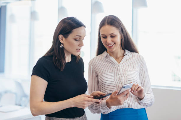 istock Two women with smartphones, using apps, looking at screens 1353596003