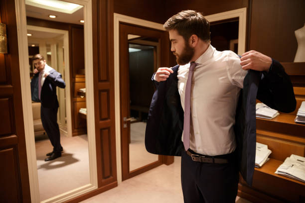 Bearded Man putting on his jacket Bearded Man putting on his jacket while looking at the mirror men Fashion stock pictures, royalty-free photos & images
