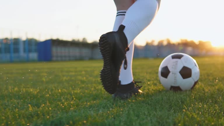 Close Up Of Female Football Player Running And Kicking Soccer Ball At Sunset