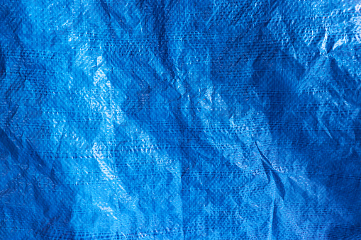 Blue plastic waterproof tarpaulin, textured background, polyethylene sheet.