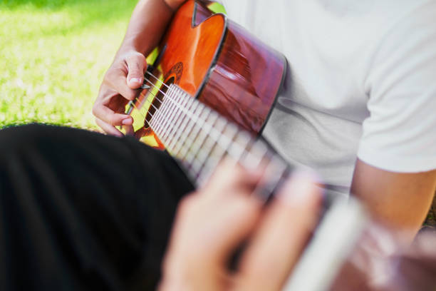 homme jouant de la guitare dans un parc ensoleillé - musical instrument nature outdoors musician photos et images de collection