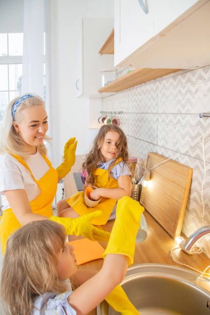 istock Caucasian Mom and two daughters wiping the table in the kitchen after cooking 1353604652