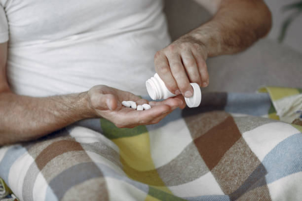 istock Senior man with pills sitting in bed 1353605710
