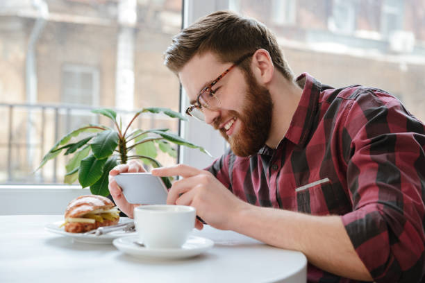 istock Smiling man with smartphone photographing his lunch at cafe 1353606626