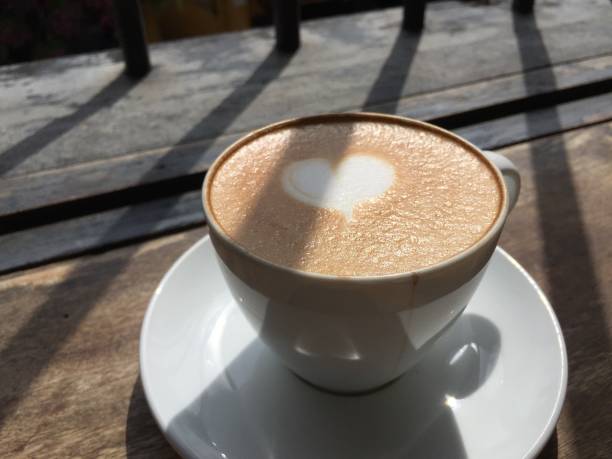 istock Cup of cappuccino coffee with sun light on the wood table 1353607313