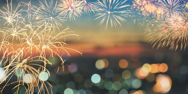 Photo of Fireworks over blur city skyline with colorful bokeh lights background