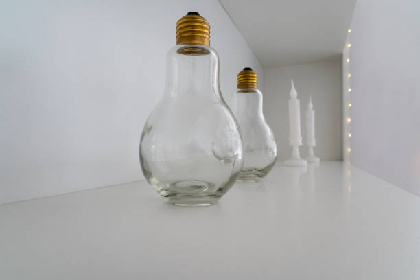 istock Two light bulbs with a gold socket standing one after another on a white background 1353609552